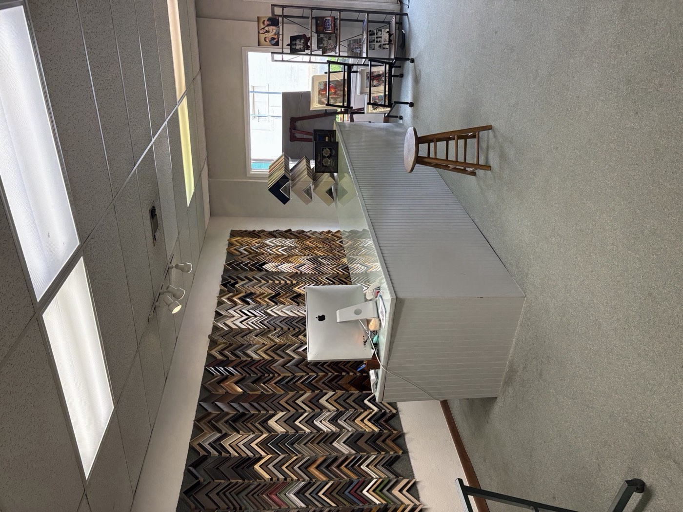 Inside The Frame Up custom framing shop in Ruston, Louisiana — counter, wall of 100+ moulding profile samples, and front window onto Vienna Street
