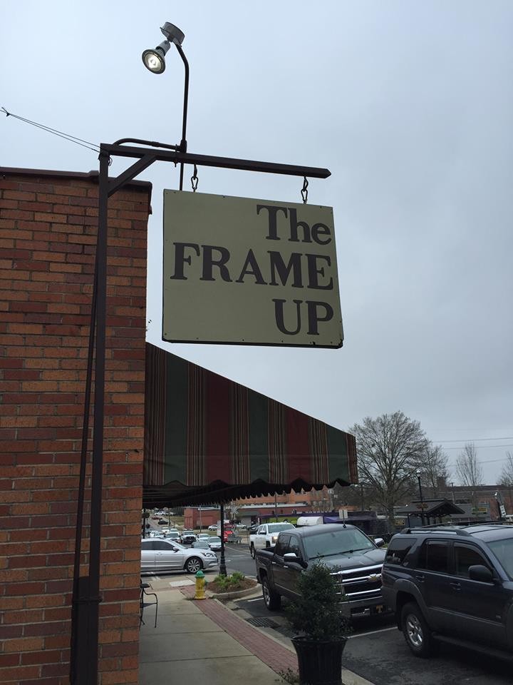 The Frame Up storefront on Vienna Street in downtown Ruston, Louisiana with brown standing-seam awning and Custom Picture Framing lettering