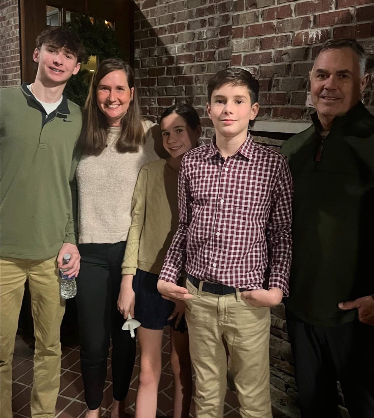 The Terry family — Christi, Lead, and their three kids on a brick patio, taken on a winter evening in Ruston